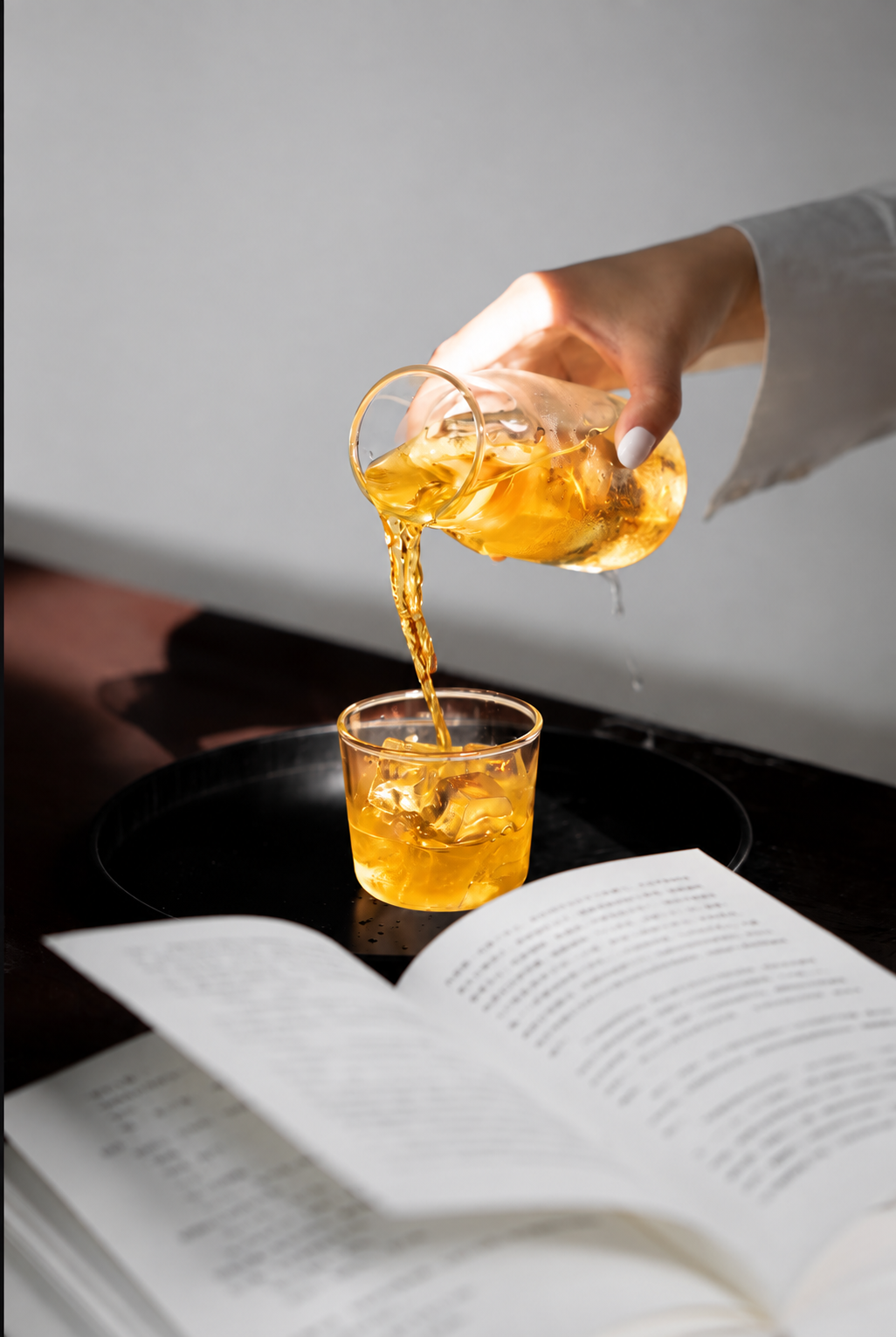 A chilled botanical drink being poured over ice